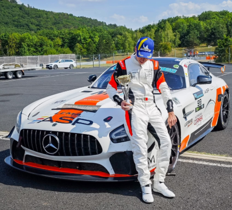 Miguel Gaspar holding a trophy in front of a Mercedes-AMG GT4