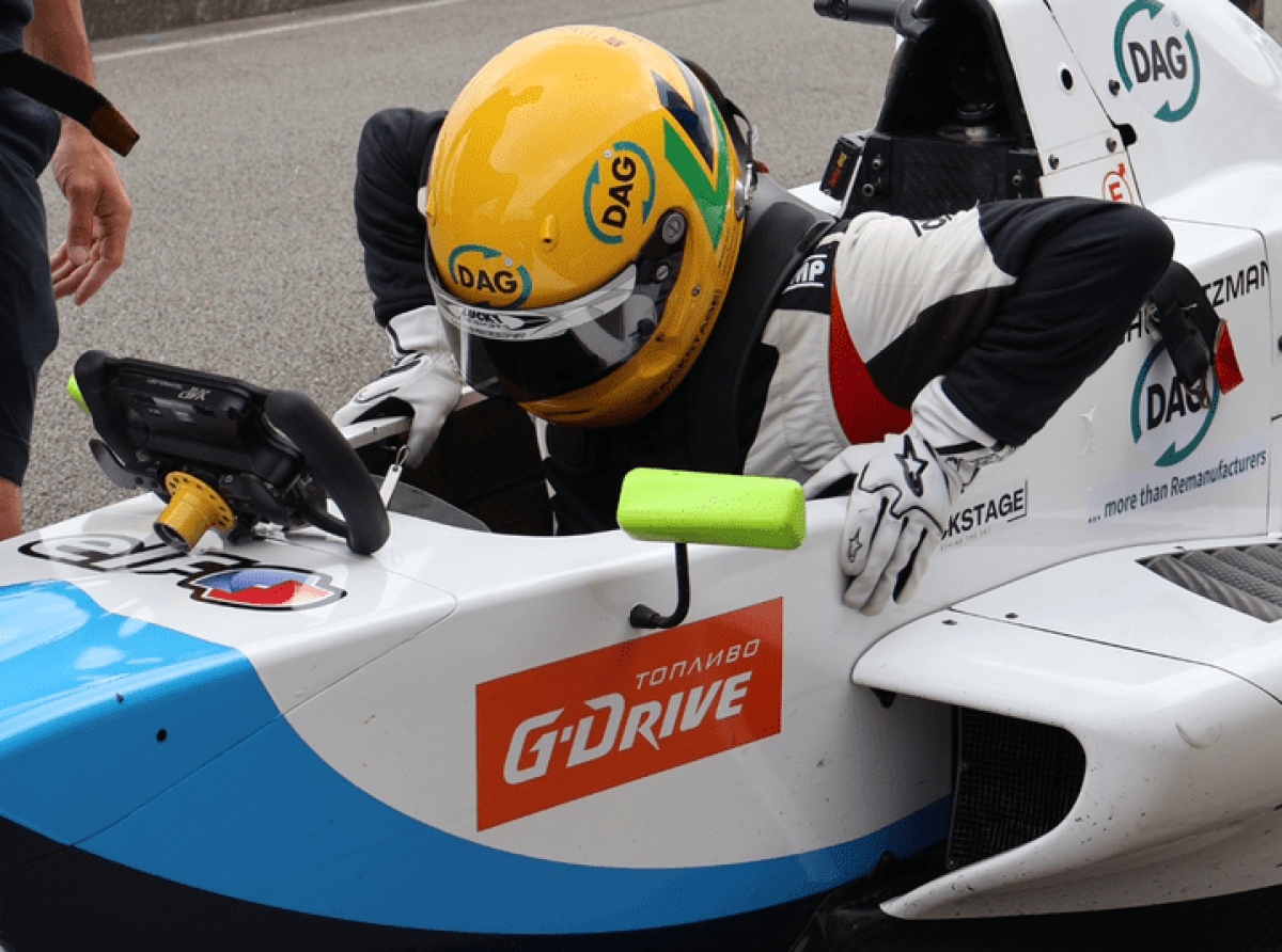 Miguel Gaspar wearing a yellow DAG helmet while getting into his Formula Renault car